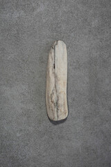Piece of White Dry Wood on a Gray Grunge Granite Structure Background ideal for Wall Art, Poster, Decoration. Minimalist Abstract Zen Composition.