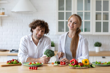 Happy couple is preparing healthy food on light kitchen. Cooking together salad