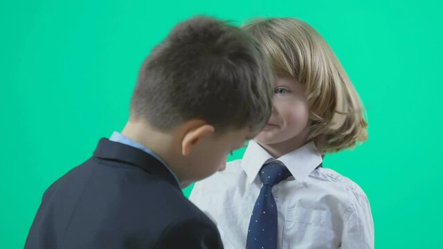 Child arrange little blonde hair boy tie, elegant dress, green background