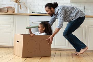 African father rides little 5s daughter in carton box, girl looks in paper tube binocular, observe,...