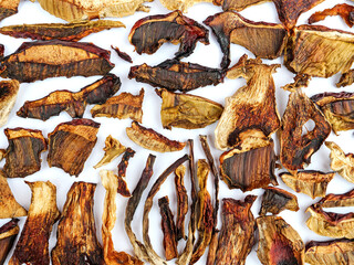 Dried brown boletus mushroom slices laying flat on white background