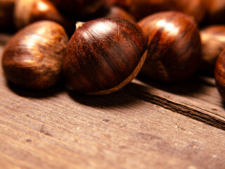 chestnuts photographed very closely, close to camera, close-up, on wooden table and morning sunlight, copy space