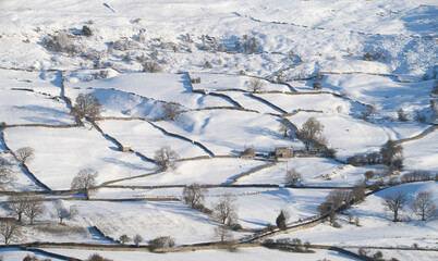 snow covered fields in the Yorkshire dales in winter showing barns and field patterns