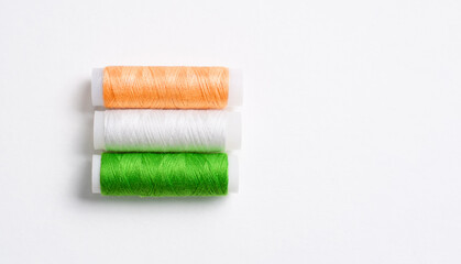Three multi-colored spools of thread for sewing, folded in the form of the flag of India on a white background. There is a free empty space.