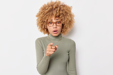 Waist up shot of shocked curly haired blonde woman holds breath from wonder cannot believe her eyes...