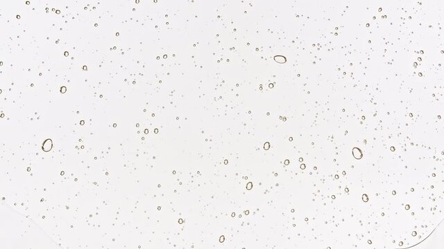 Transparent cosmetic gel fluid with bubbles oil on water silver colored background. Macro Shot. High quality 4k footage