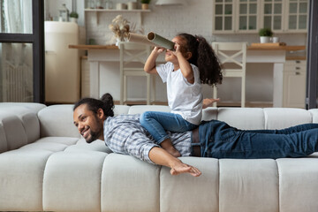 African girl sit on dad back looks into paper tubes into distance, play spy or stargazer imagining...