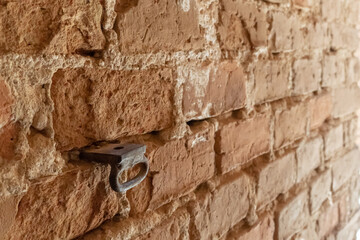 The surface is made of old red brick. A wall of old historical knowledge and broken and broken bricks and protruding metal pins. Blank background for the design