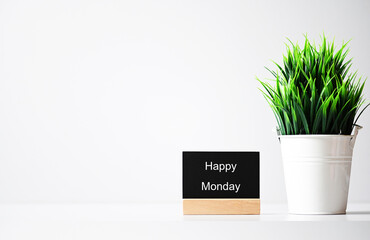 Happy monday message label on table and green plants in pots