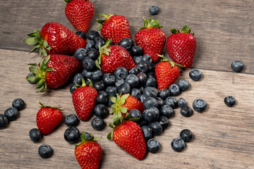 various strawberries and blueberries leaning on a wooden table