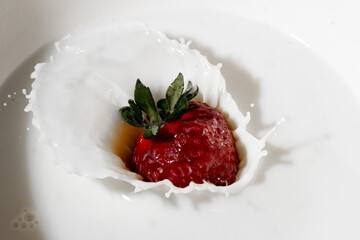 a strawberry falling into a pot full of milk