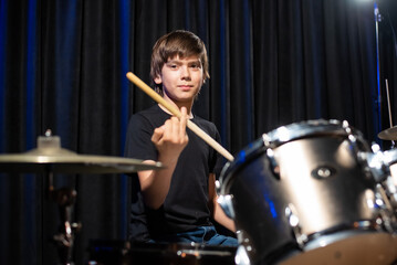 Obraz na płótnie Canvas A boy plays drums in a recording studio