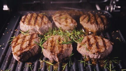 Delicious juicy meat steak cooking on grill. Prime beef fry on electric roaster, rosemary, black pepper, salt. Slow motion.