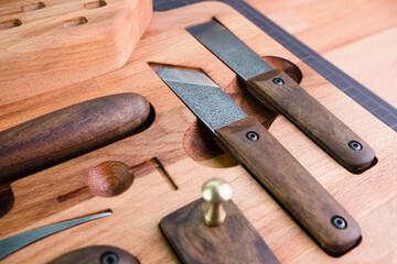 Exclusive handmade leather craft tools. Close up of different tanner tools on wooden box. Set of Different knifes from steel and wood. Black background.