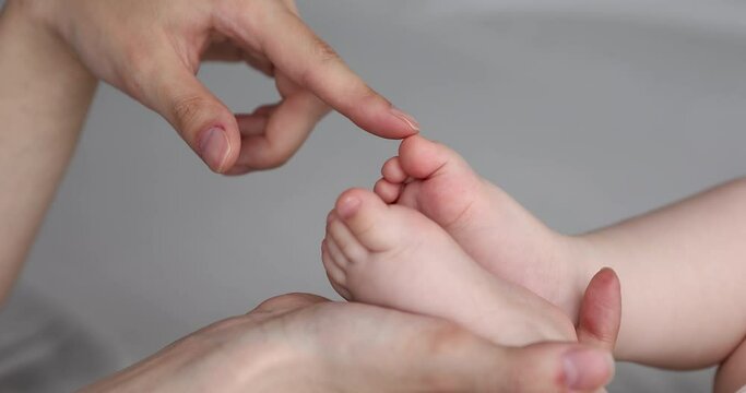 Sweet feet. Close up happy mom hand tender caress with finger cute chubby toes of newborn infant baby kid. Affectionate mother feel emotional connection with child enjoy healthy skin on babe bare feet