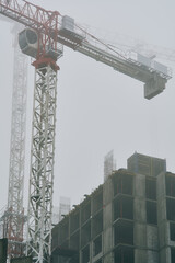 High-rise cranes next to buildings under construction. Kyiv, Ukraine. Fog in the city.