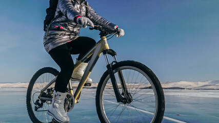 Obraz premium Woman is riding bicycle on the ice. Tires on bike are covered wi
