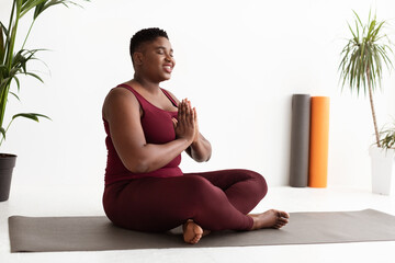 Peaceful fat black lady in sports outfit meditating