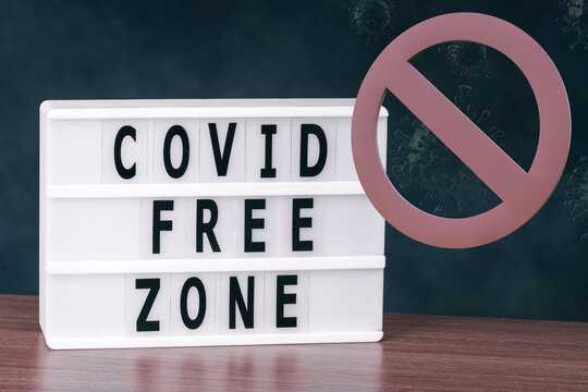 Covid free zone spelled in letters on lightbox with stop sign on dark background