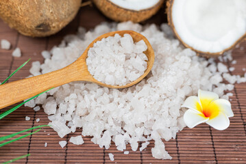sea ​​salt in a wooden spoon with coconut for beauty care and mango flowers