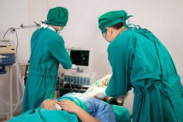 Team doctor and assistant holding oxygen mask with patient emergency and looking monitor in the operation room at hospital, surgeon healing and surgery, problem of breathing, medical and health.