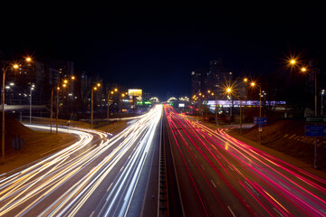 Light trails from fast moving cars at night. Large ring road with heavy traffic
