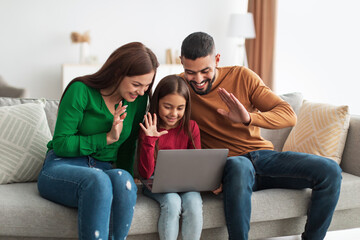 Arab family making video call using laptop waving hands