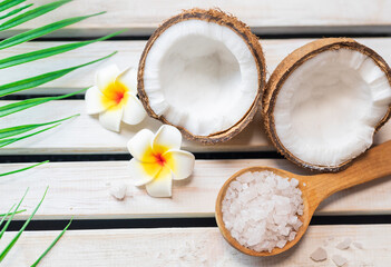 Fototapeta na wymiar sea ​​salt in a wooden spoon with coconut for beauty care and mango flowers