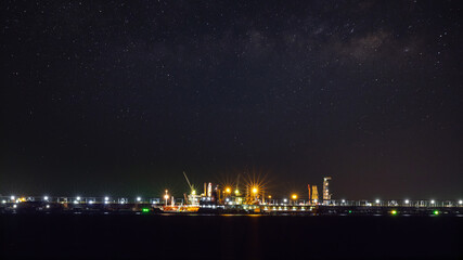 Oil ship tanker loading oil at the oil brige on the sea from refinery for transportation. at night over lighting and starlight background process
