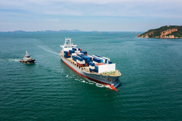 aerial in front view container ship and tugboat dragging floating in green sea, business and industry Transportation cargo logistics services of international by container ship in ocean