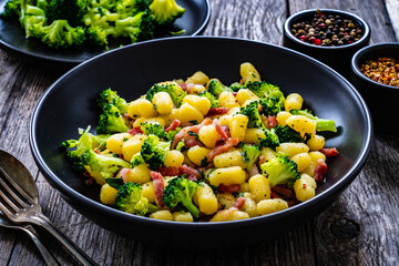 Gnocchi with bacon and broccoli on wooden table
