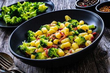 Gnocchi with bacon and broccoli on wooden table
