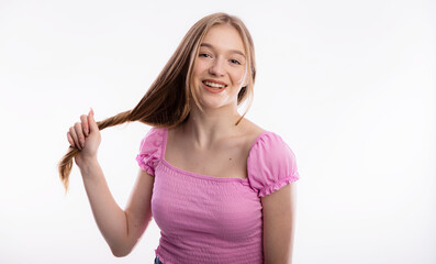 Cute young woman pulling her long blond hair. Beautiful female holding hair up on white background copy space. Care and health concept of the head and hair