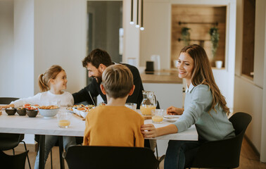 Young happy family talking while having breakfast at dining table