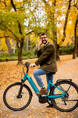 Fototapeta na wymiar Young man with electric bicycle in the autumn park