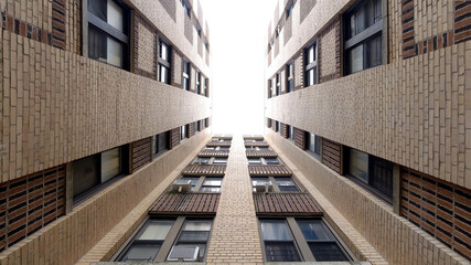 Upward looking perspective of cloudy sky through a framing of residential block in the Bronx, New York City. Fine art photograph.