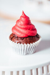 Chocolate cupcakes or muffins decorated as Christmas tree with buttercream. Ginger house and Christmas lights from Christmas tree in blurry background. Festive and holiday decoration