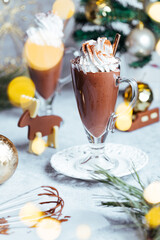 Hot chocolate with wiped cream on top in Christmas decoration with lot chocolate figures. Festive and holiday mood and atmosphere