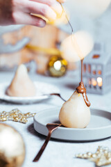 Cooked pear poached with melting chocolate served as dessert to celebrate Christmas or New year. Decorated in holiday spirit and mood with lot of decoration and lights