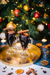Mulled wine with cinnamon, anise star and orange served in festive Christmas decoration in front of a Christmas tree and lights. Ideal drink for advent and celebration.