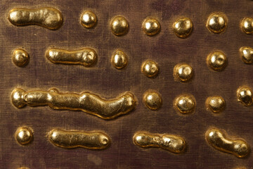 Round drops and drips of gold metal on the surface of the board - 474521872