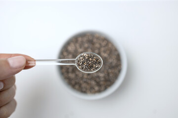 Chia seeds in glass spoon and cup from top view with space on white background with copy space, view from above