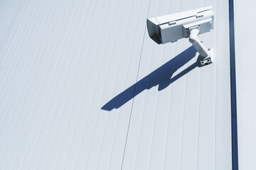 White street surveillance camera on the white wall of the building.