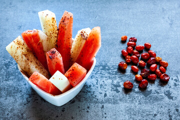 Fruit sticks with chili spice. Fresh raw sweet cut fruit with spicy chile and cocoa condiment powder. Summer snack.