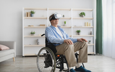 Happy senior man in wheelchair wearing VR glasses, playing online video game in cyberspace at home