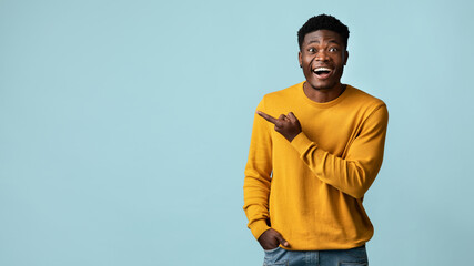 Cheerful african american millennial man pointing at copy space