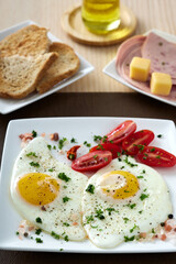 Fried eggs with cherry tomatoes, cheese and salami