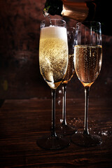 Glasses of champagne with bottle on dark wooden background.. Vertical close-up.