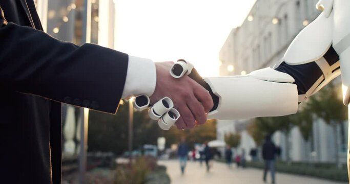 Hand of a businessman shaking hands with android robot. The concept of human interaction with artificial intelligence
