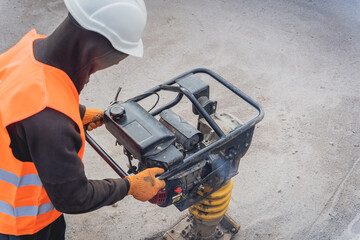 Worker uses a portable vibration rammer at construction of a power transmission substation